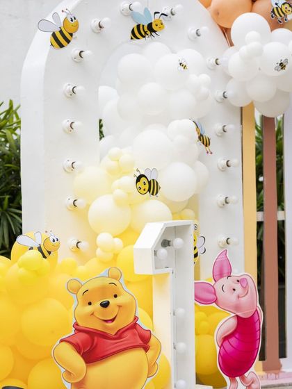 A close-up of the Winnie the Pooh stage, featuring a light-up number '1', Pooh and Piglet cutouts, and balloon clouds with cute bee accents.