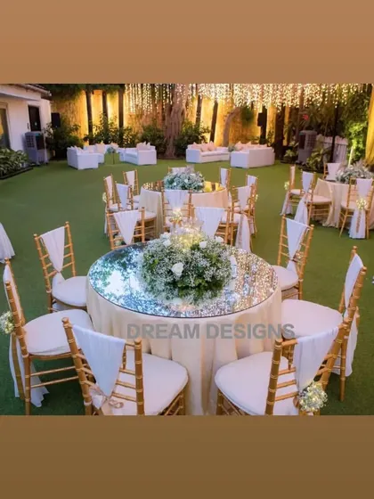 A dreamy setup for a meet and greet function. The space features elegant round tables with mirrored tops and a comfortable lounge area, all under a canopy of warm, twinkling lights.
