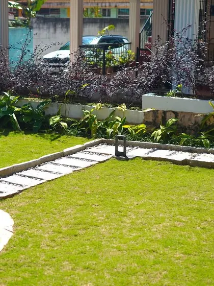 A different angle of the residential garden, showing the relationship between the raised plant beds, the lawn, and the stone well feature.