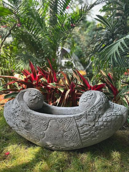 Out with the old, in with the bold. This uniquely shaped stone planter features intricate carvings and a curved, boat-like form, making it a true conversation piece for any garden.