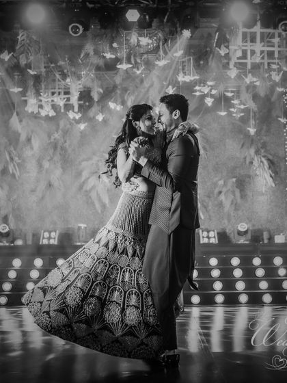 A timeless black and white photo of the couple's first dance. The dramatic backlighting and the bride's flowing lehenga create a moment of pure cinematic romance.
