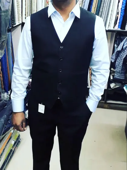 A classic black V-neck waistcoat paired with a light blue shirt and matching trousers. This timeless combination is something I tailor for a perfect fit.