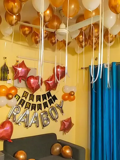 A closer view of the 'Happy Birthday Raaboy' setup, showing the arrangement of foil and latex balloons over the sofa.