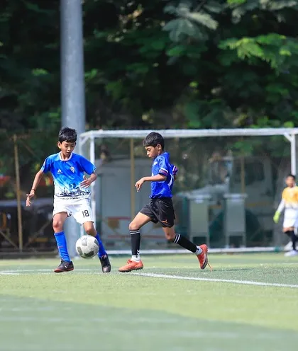 Two players challenge for the ball in a competitive U13 fixture.