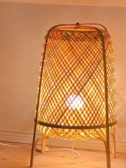 This woven bamboo table lamp provides a warm, ambient glow perfect for a bedside table or living room accent. Its sturdy frame and intricate weave showcase the versatility and beauty of handcrafted bamboo decor.