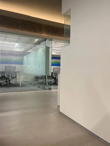 A view down a hallway in the Umicore office, showing the use of frosted glass for privacy in meeting rooms and an overhead accent panel made from sustainable materials, reinforcing the brand's ethos.