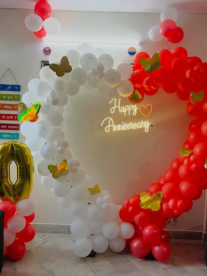 A close-up of the anniversary heart arch, decorated with butterfly cutouts and a neon sign.