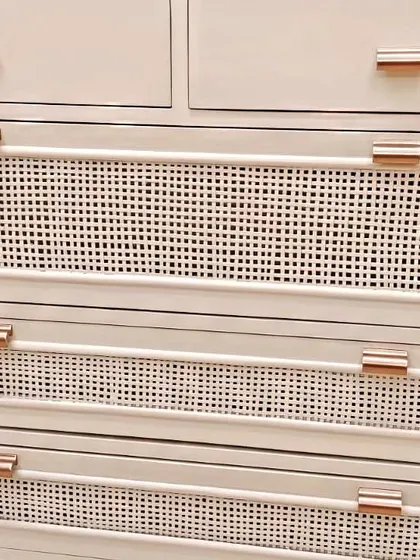 A close-up of the cane webbing and rose gold handle on our custom-made chest of drawers. This combination of natural texture and modern hardware creates a sophisticated look.