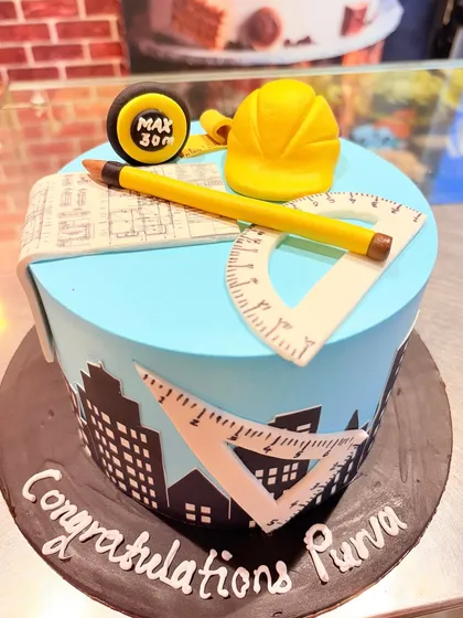 An architect or civil engineer's cake, featuring a city skyline, blueprints, and drafting tools like a protractor and set square.