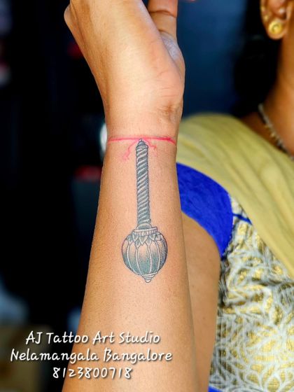 A tattoo of Hanuman's mace (gada) on the wrist, symbolizing strength and devotion.