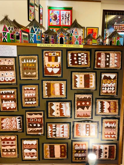 A display from our "Colours of Africa" exhibition, featuring African mud cloth-inspired art and miniature huts created by students aged 3 to 7.