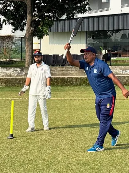 A coach demonstrates the correct bat swing and follow-through during a personal coaching session. This one on one attention is key to refining a player's technique.