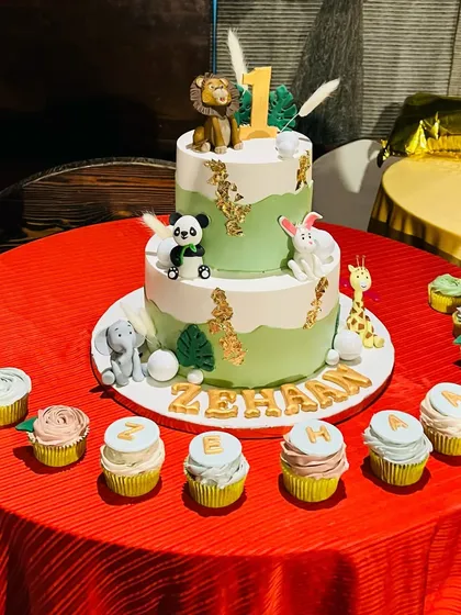 The final setup of the two-tier jungle animal cake for Gauahar Khan's son's first birthday, complete with matching cupcakes spelling out his name.