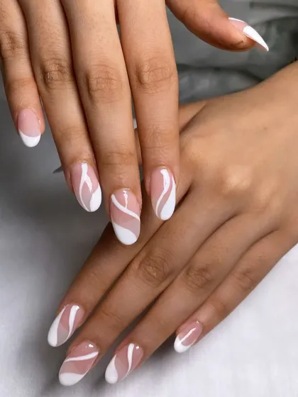 A modern take on a classic. This look features elegant almond-shaped nails with a creative, swirling twist on the traditional French manicure.