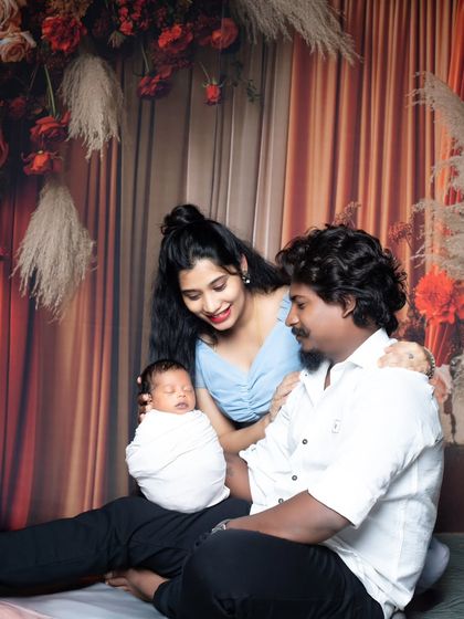 A beautiful family portrait with parents looking lovingly at their newborn baby, who is swaddled and resting.