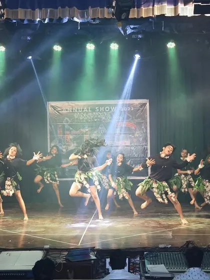 A wide shot of the tribal dance, showing the entire group moving across the stage with high energy and synchronized steps.