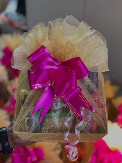 A simple yet elegant welcome hamper, beautifully wrapped in net with a large pink bow. It's filled with snacks and essentials to make wedding guests feel right at home.