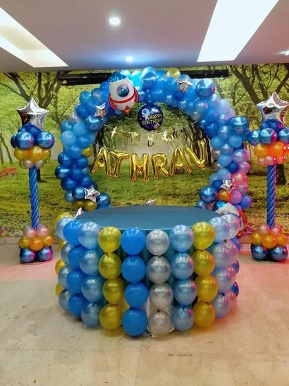 An outer space theme decoration for Athrav's birthday. We created a unique cake table display using balloons to form a well, topped with a balloon arch, rocket ship foils, and the birthday boy's name.