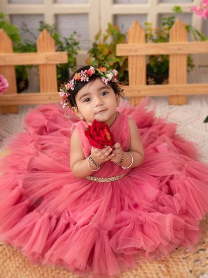 A nine-month-old princess holding a single red rose. This sweet gesture adds a touch of romance and elegance to the portrait.