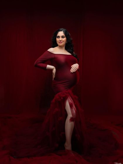 A full-length portrait showcasing a magnificent off-the-shoulder red gown. The rich color and mermaid-style tulle train create a classic, high-impact look that is both elegant and unforgettable.