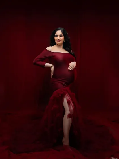 A full-length portrait showcasing a magnificent off-the-shoulder red gown. The rich color and mermaid-style tulle train create a classic, high-impact look that is both elegant and unforgettable.