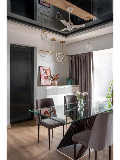 To make the dining space feel larger and more glamorous, I installed a black tinted mirror on the ceiling. This reflects the light from the modern chandelier and the entire room, adding depth and a unique design statement.