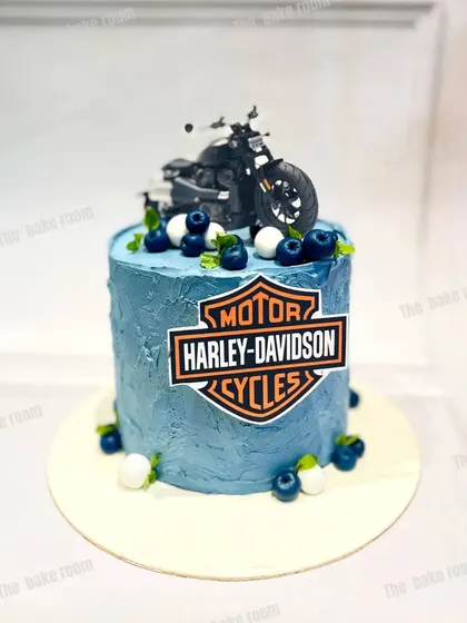 A cool Harley-Davidson themed cake for a motorcycle enthusiast. The cake features the iconic logo and is topped with a detailed model of a Harley bike.