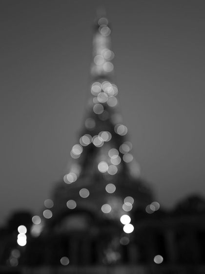 An abstract, out-of-focus shot of the Eiffel Tower's lights at night. The bokeh creates a dreamy, impressionistic interpretation of the famous landmark.
