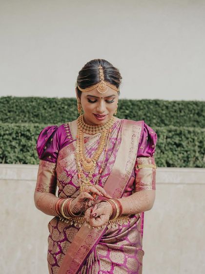 A quiet moment of reflection before the ceremony. This South Indian bride looks serene and beautiful in her purple Kanjeevaram, with makeup that is both traditional and sophisticated.