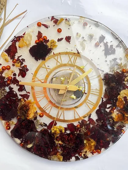 A simple yet elegant design. This 12-inch clock features preserved red and white rose petals scattered on a clear base, with a small, classic dial.