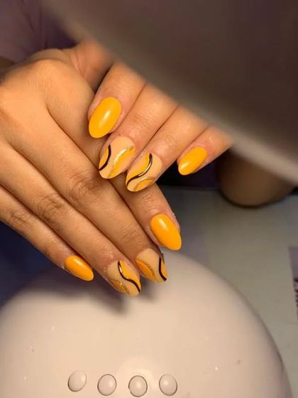 A cheerful set of bright yellow nails with abstract black swirl accents.