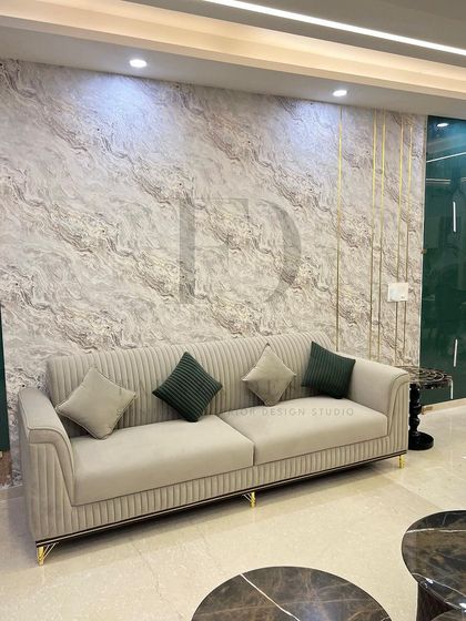 A detailed shot of the vertically-tufted beige sofa, set against a textured wallpaper with inlaid gold-toned strips. This highlights our attention to detail in combining textures and materials.