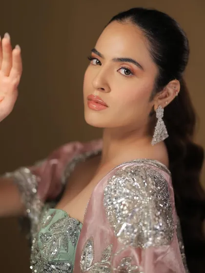 A playful and confident pose. The peachy tones on the cheeks and lips give a fresh and youthful glow.
