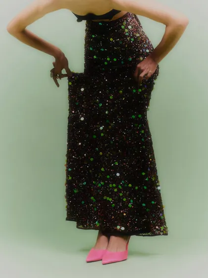 A full-length shot that shows the jewelry styled with a sequined skirt and bright pink heels. This image is about creating a fun, high-energy party look.