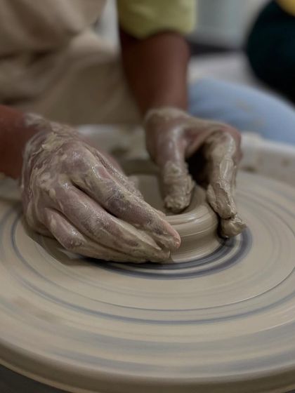 Getting your hands muddy is part of the fun. Here, a student is learning to center the clay, which is the most important skill for wheel throwing.