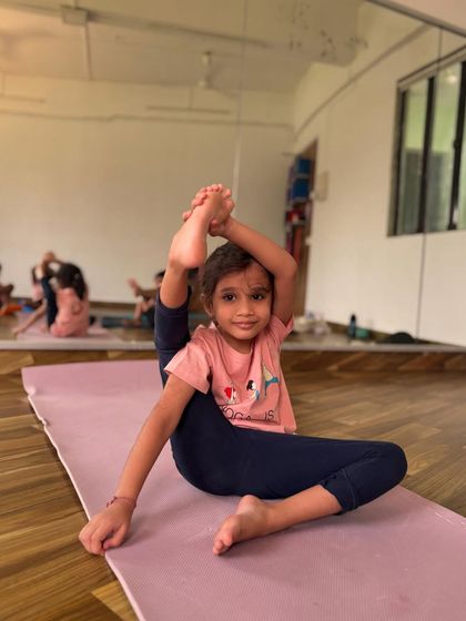 This little girl has found such grace in this challenging leg-behind-head prep pose. It's a testament to how consistent and joyful practice can lead to amazing results.