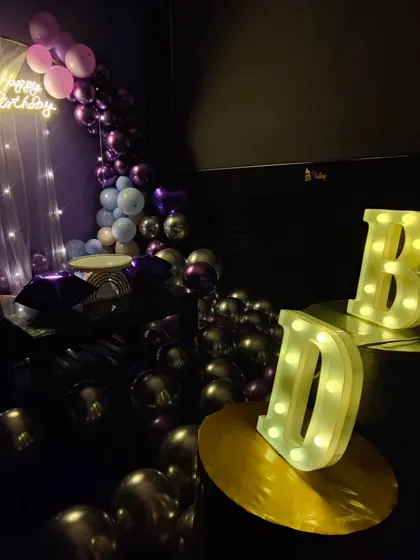 This setup combines a balloon arch with large, illuminated 'HBD' marquee letters. It's a great option for creating a dedicated photo corner at your birthday party.