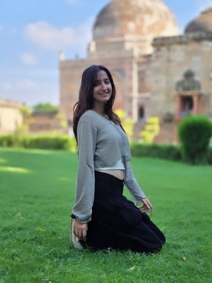 A relaxed, kneeling pose on the grass. This casual portrait feels natural and unforced, perfect for capturing a laid back afternoon in the park.