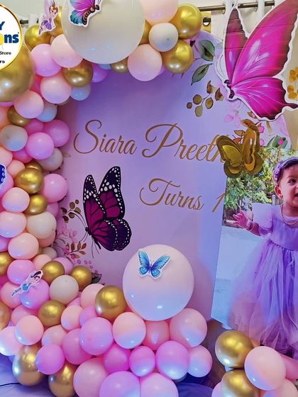A lovely butterfly-themed first birthday with a photo of the birthday girl. The pink and gold balloon arch and butterfly details create a warm and celebratory feel.