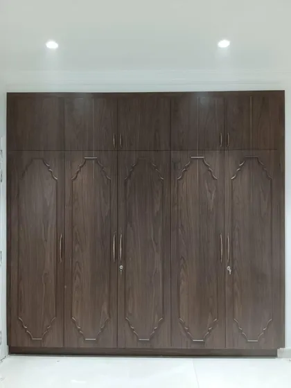 A custom-designed wardrobe with a classic touch. The dark wood finish and traditional molded details on the shutters provide a timeless elegance, while the full-height design offers ample storage.