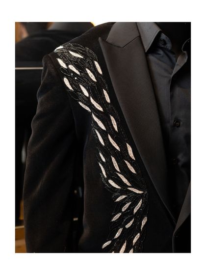 A detail shot of the shoulder and lapel of our black velvet blazer. The hand-embroidered silver design flows elegantly down the sleeve, adding a touch of artistry to a classic silhouette.