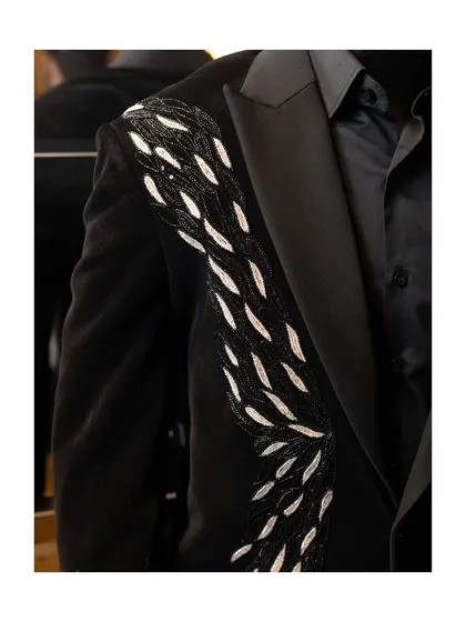 A detail shot of the shoulder and lapel of our black velvet blazer. The hand-embroidered silver design flows elegantly down the sleeve, adding a touch of artistry to a classic silhouette.