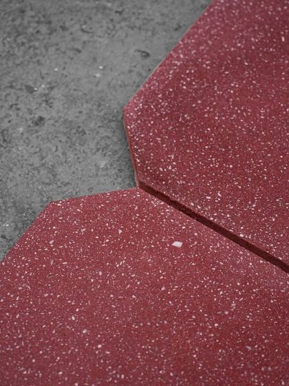 A close-up of our octagon-shaped terrazzo tiles in a deep, rich red. The unique shape allows for creative flooring patterns.