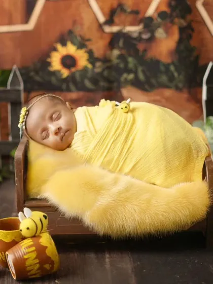 A slightly different angle of the honeycomb backdrop setup, capturing the sleeping newborn in a warm, golden light.