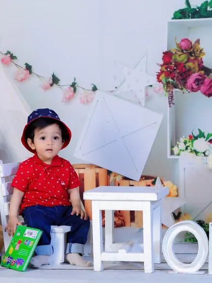 A little boy in a cute hat sits at a small table in our bright, boho-chic setup, celebrating his first birthday with style.