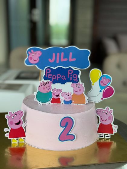 A sweet Peppa Pig theme cake for a 2nd birthday celebration. All characters and decorations are created with edible toppers on a smooth, creamy frosting base, making it completely kid-friendly and delicious.