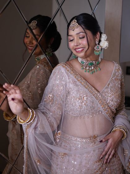 A beautiful reflection shot capturing the bride's joyful smile. The soft hairstyle with fresh flowers adds a romantic touch to her overall look.