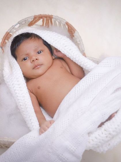 A beautiful overhead shot of a newborn resting in a basket, wrapped in a white blanket. This angle highlights how small and precious they are.