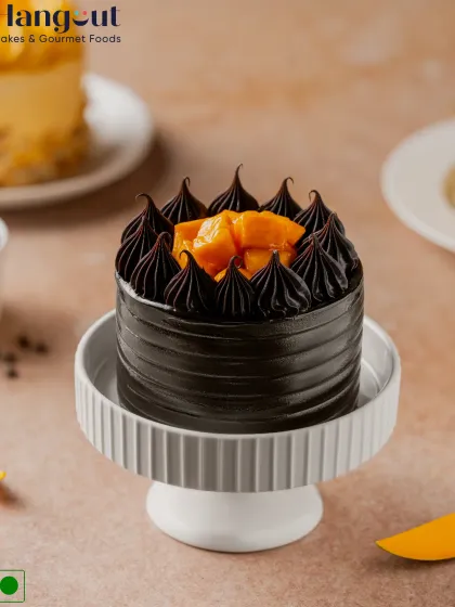 Our Mango Chocolate Truffle Bento Cake features layers of rich chocolate sponge and cream, covered in smooth ganache and topped with fresh, pulpy Alphonso mango pieces.