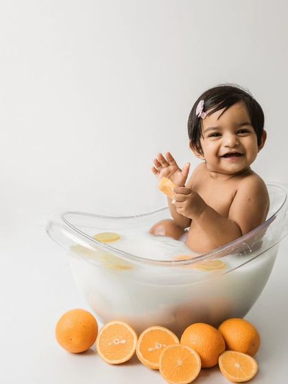 A big, happy smile from the little girl in the orange and lemon fruit bath.